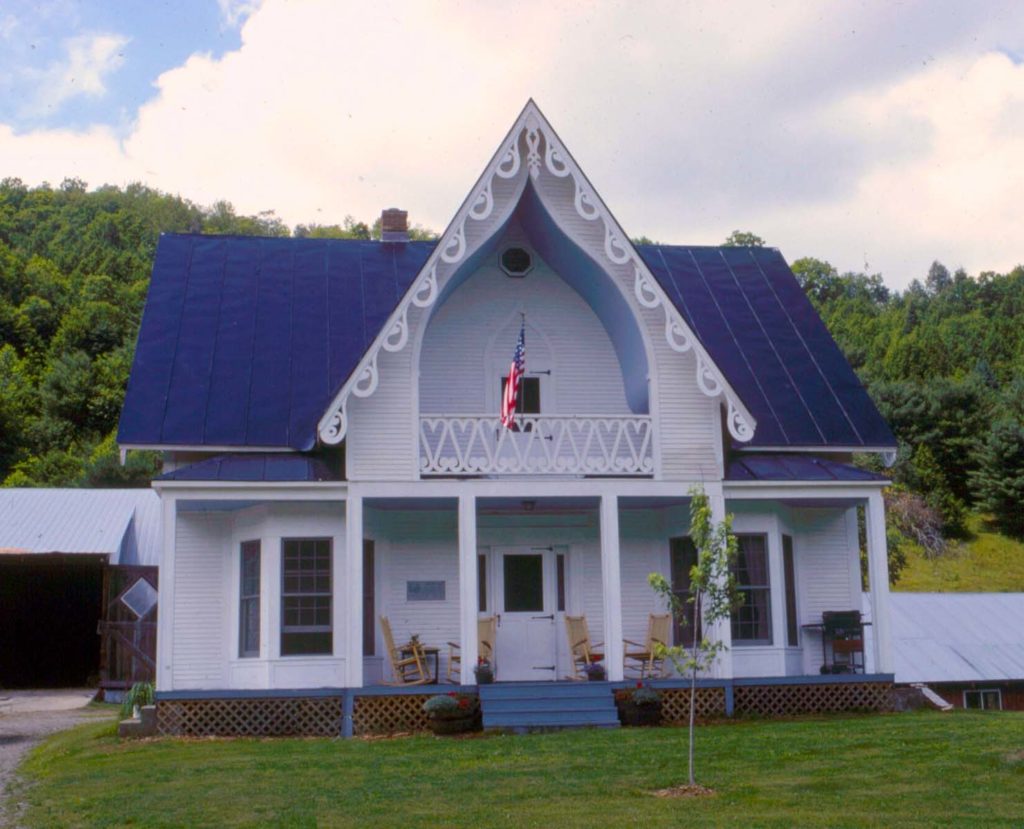 A simple carpenter Gothic Revival House features a fanciful barge board and steeply pitched roofs