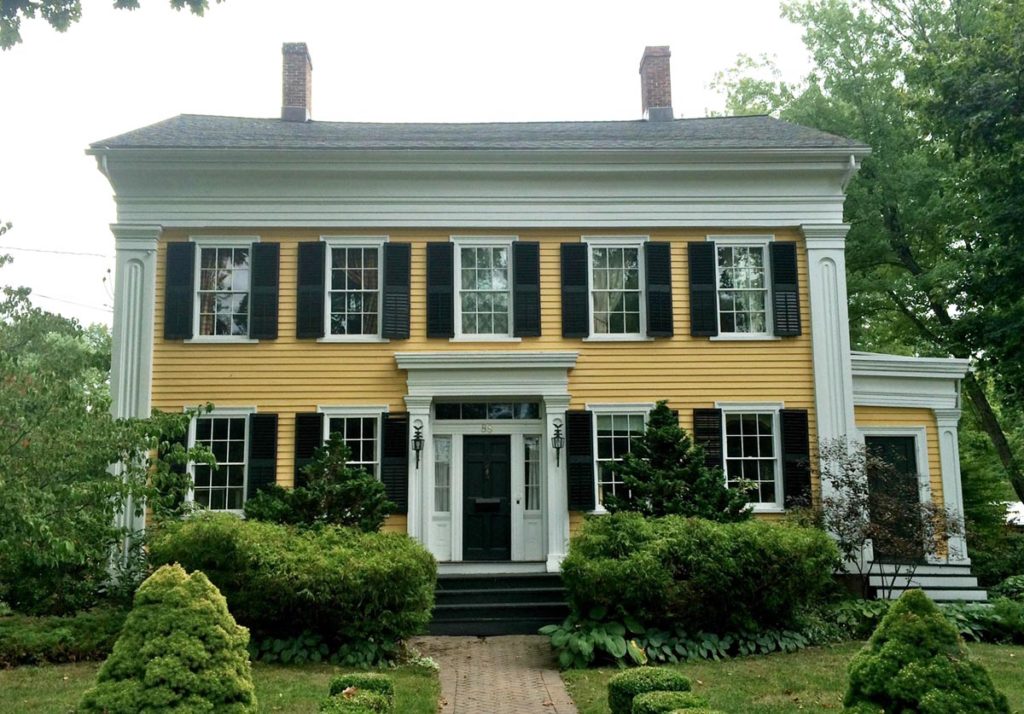 This house sports very fancy quoins/pilasters, and an inset portico, all full embellished with Greek revival designs, but the entry door is on the long side of the building, and the array of the windows is decidedly Georgian/Federal. 