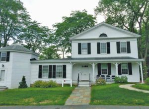 Greek Revival house with Colonial Revival porch and an ell attaching an octagonal outbuilding.