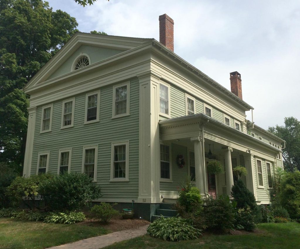 A quirky Greek Revival with the gable end facing the street and a side entrance and a fairly substantial porch with Ionic columns. 