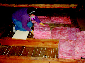 Installing batts insulation in the attic bays. Be sure to wear proper clothing and a mask