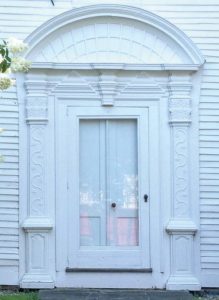 This portico entry on a Georgian style house has a profusion of compound heavily-molded capitals, vine carvings, raised panels and a delightful fanned roof.